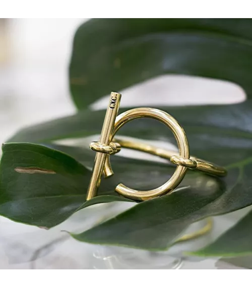 Pulsera Orígenes CXC, en metal bañado en oro.