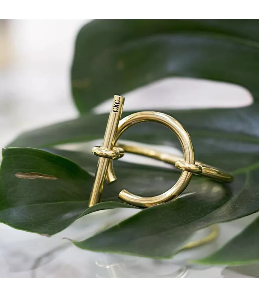Pulsera Orígenes CXC, en metal bañado en oro.